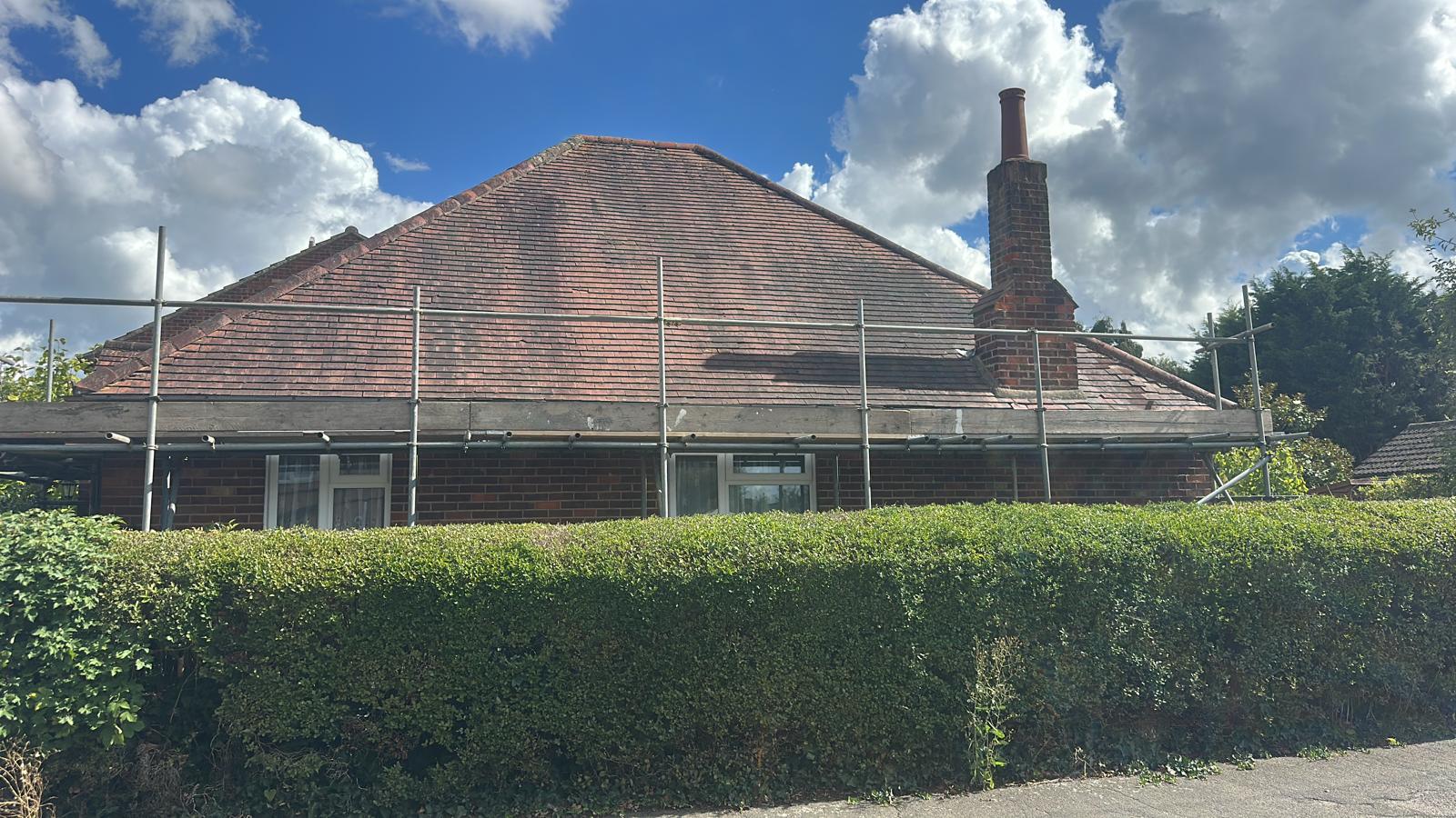 Completed clay plain tile re-roof on bungalow with hipped roof and scaffolding