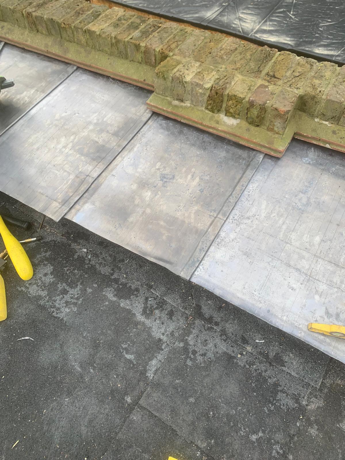 Traditional slate roof with dressed lead valley flashing and weathered clay ridge tiles on a North London residential property